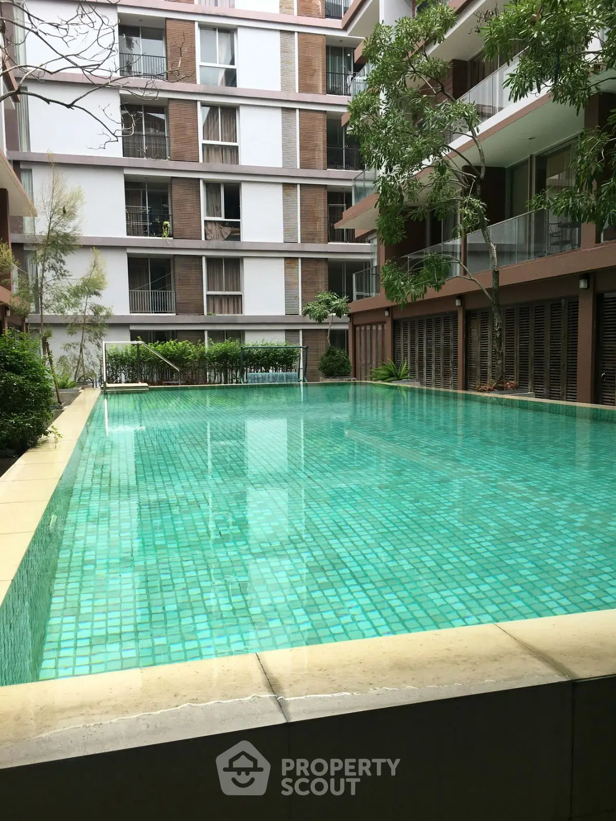 Luxurious apartment complex with serene swimming pool and lush greenery