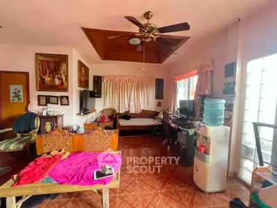 Spacious living room with traditional decor and ceiling fan, featuring natural light and cozy seating area.