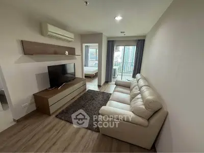 Modern living room with leather sofa, TV, and city view balcony in stylish apartment.