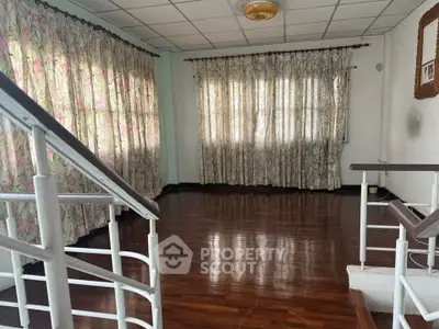 Spacious living room with wooden floors and floral curtains, ideal for cozy gatherings.