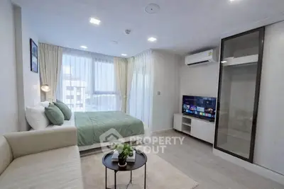 Modern studio apartment with cozy living area and stylish bedroom, featuring natural light and sleek design.