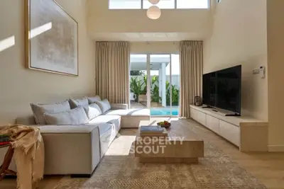Luxurious living room with modern decor and pool view, featuring a spacious sofa and large TV.