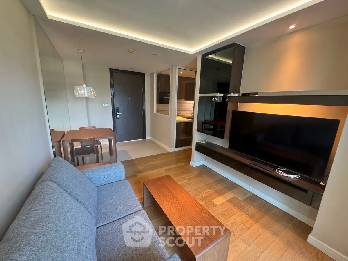 Modern living room with sleek design, featuring a cozy sofa, wooden flooring, and a wall-mounted TV.