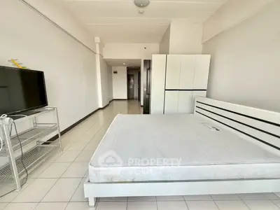 Spacious bedroom with minimalist design, featuring a large bed and modern TV setup.