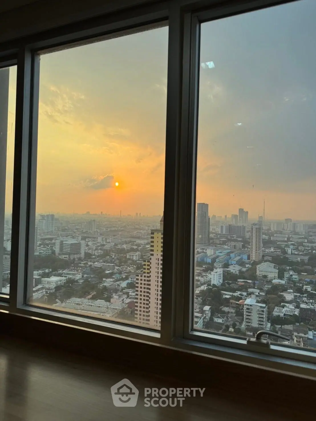 Stunning cityscape view from high-rise apartment window at sunset.
