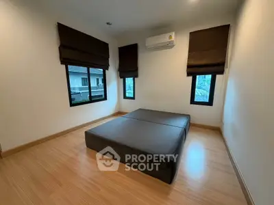 Spacious bedroom with minimalist design and large windows for natural light.