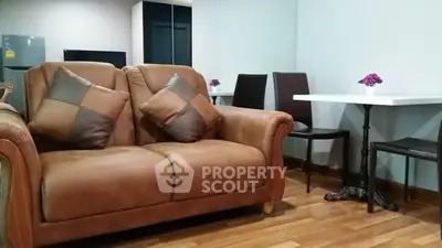 Cozy living room with brown leather sofa and dining area