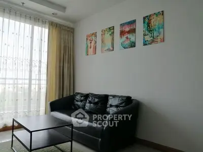 Modern living room with black leather sofa and colorful wall art, perfect for stylish urban living.