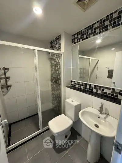 Modern bathroom with sleek shower enclosure and stylish black and white tile accents.
