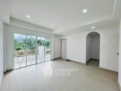 Spacious living room with large windows and balcony access, offering abundant natural light and serene views.