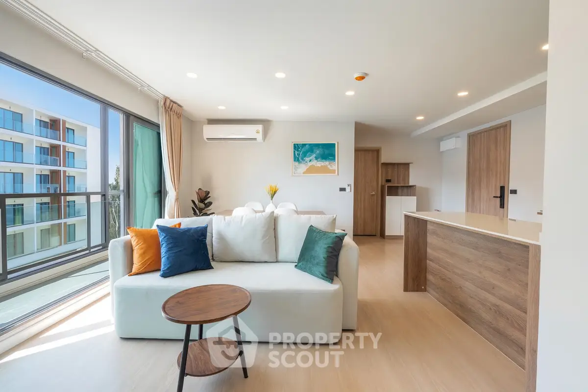 Modern open-plan living room with stylish decor and large windows in a contemporary apartment.