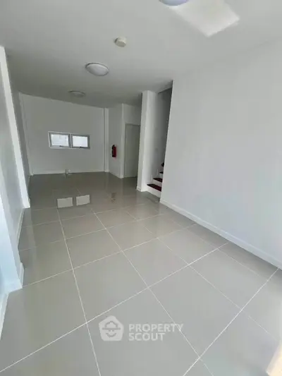 Spacious empty room with glossy tiled flooring and white walls, ideal for customization.