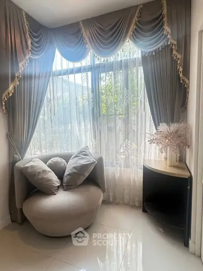 Elegant corner with plush chair and decorative curtains in a bright room.