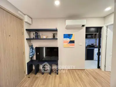 Modern living room with sleek TV stand and air conditioning, adjacent to a stylish kitchen with washing machine.