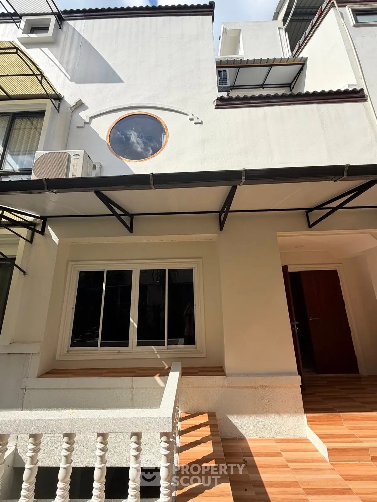 Charming townhouse exterior with unique round window and modern design elements.