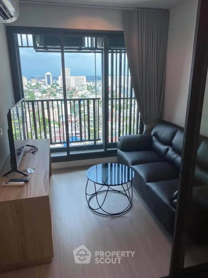 Modern living room with stunning city view, featuring sleek black sofa and stylish round coffee table.