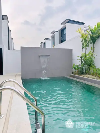 Luxurious modern pool with waterfall feature in a stylish residential complex.