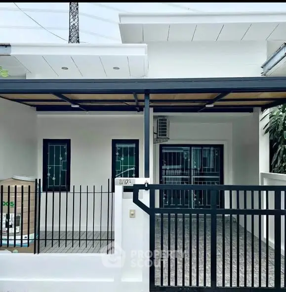 Modern single-story house with gated entrance and covered parking area.