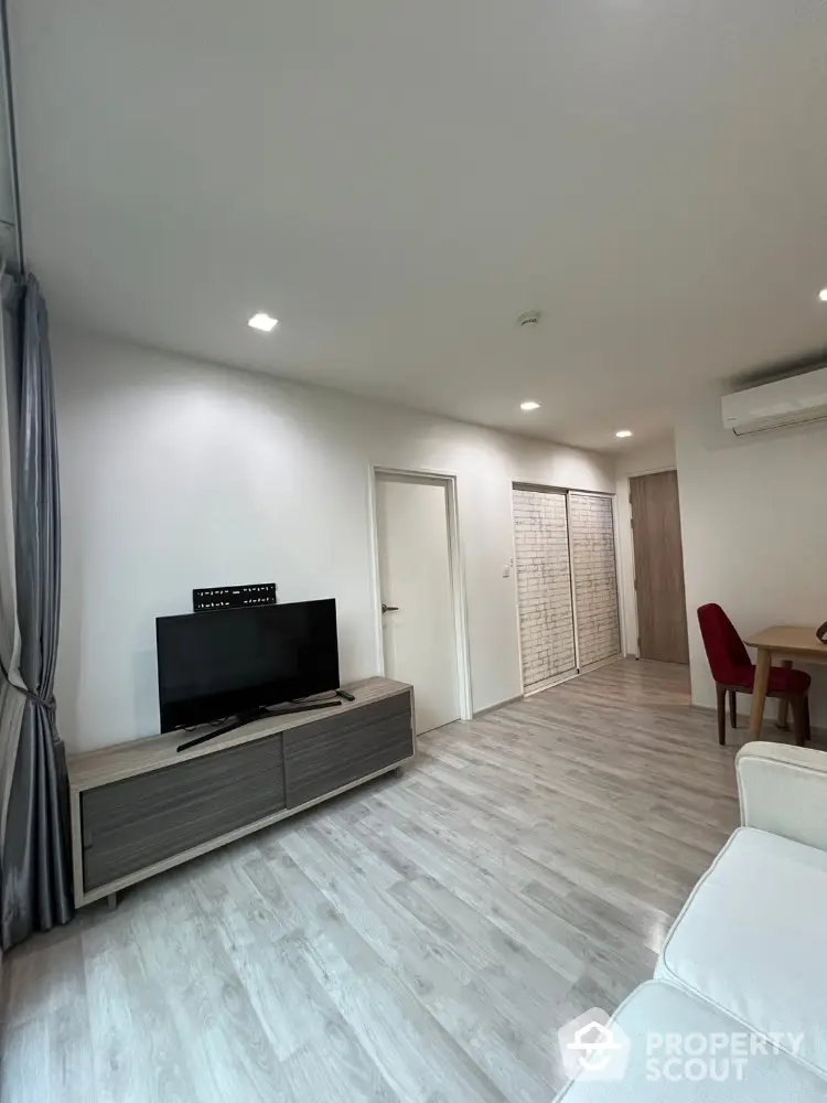 Modern living room with sleek TV stand and dining area, featuring elegant flooring and ambient lighting.