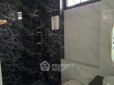 Modern bathroom with elegant black marble tiles and sleek shower design.