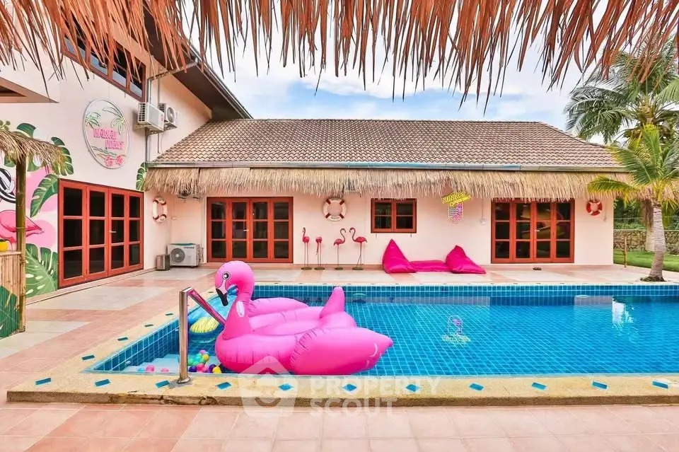 Tropical villa with vibrant pool and flamingo float, perfect for luxurious relaxation.