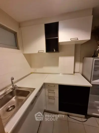 Modern kitchen with sleek white cabinets and stainless steel sink, perfect for culinary enthusiasts.