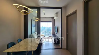 Modern living room with city view, stylish lighting, and elegant dining area in a high-rise apartment.