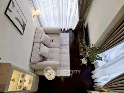 Modern living room with cozy sofa and elegant decor, featuring floor-to-ceiling windows and stylish curtains.