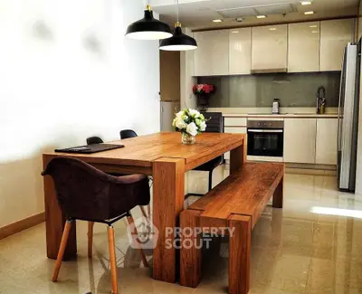 Modern kitchen with sleek cabinetry and wooden dining set, perfect for stylish living.