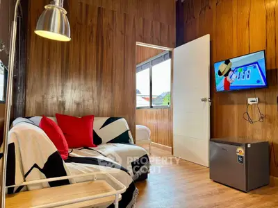 Cozy living room with modern decor and wall-mounted TV, featuring wooden paneling and natural light.