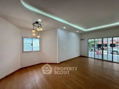 Spacious living room with modern lighting and large windows offering street view.