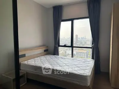 Cozy bedroom with city view, featuring a large window and modern furnishings.