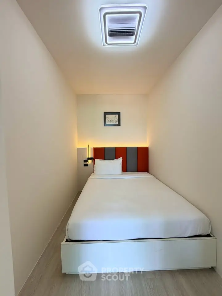Cozy minimalist bedroom with modern lighting and stylish headboard, perfect for a restful retreat.