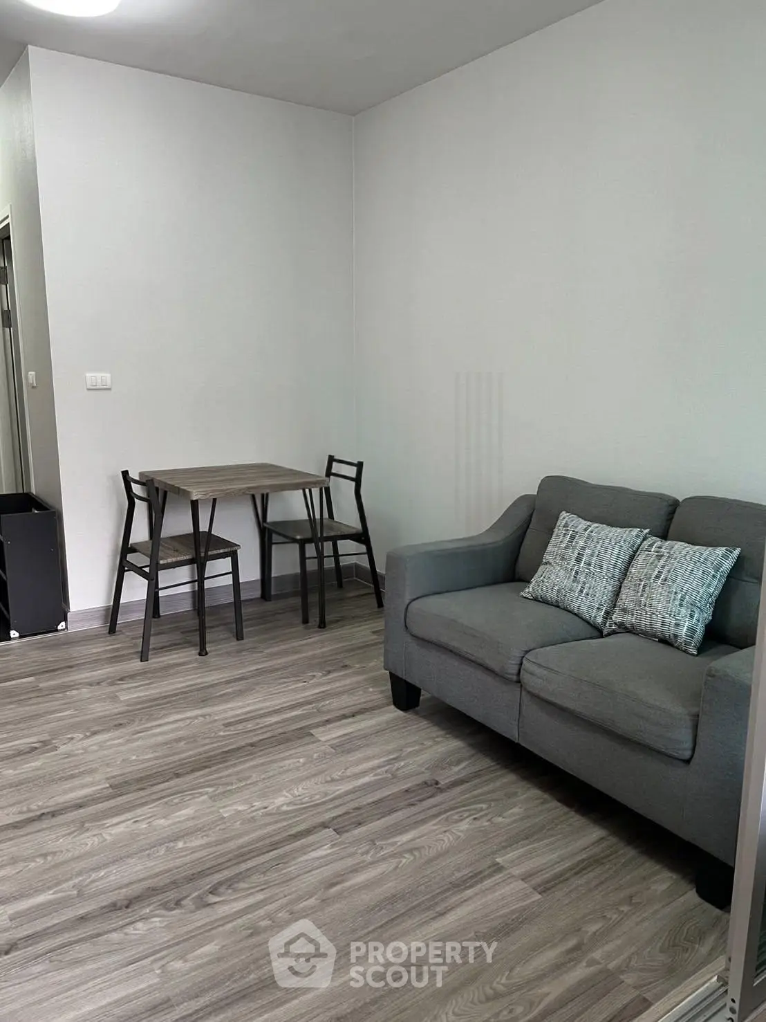 Cozy living room with modern gray sofa and dining table, perfect for urban living.