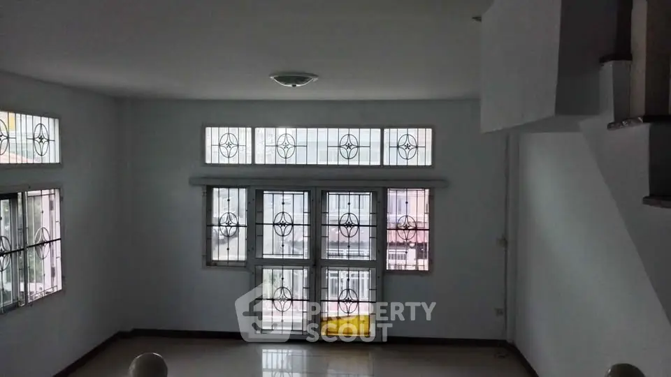 Spacious living room with large windows and decorative security bars.