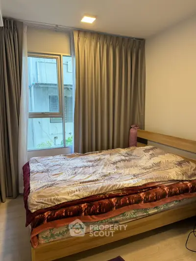 Cozy bedroom with modern decor and large window offering natural light.