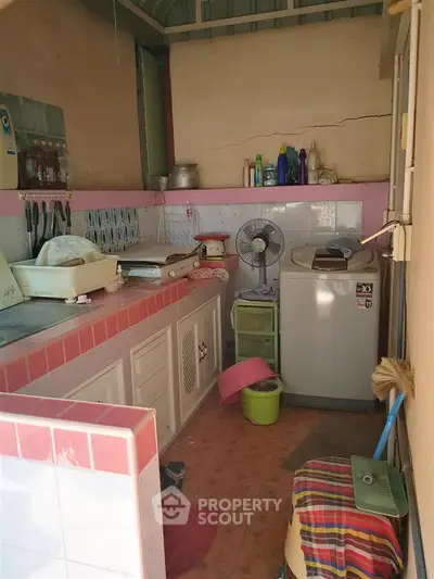 Cozy kitchen with pink tile accents and essential appliances in compact layout