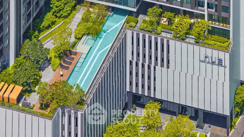 Stunning aerial view of modern building with rooftop pool and lush greenery, perfect for urban living.