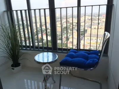 Charming balcony with city view, modern chair, and potted plant, perfect for relaxation.