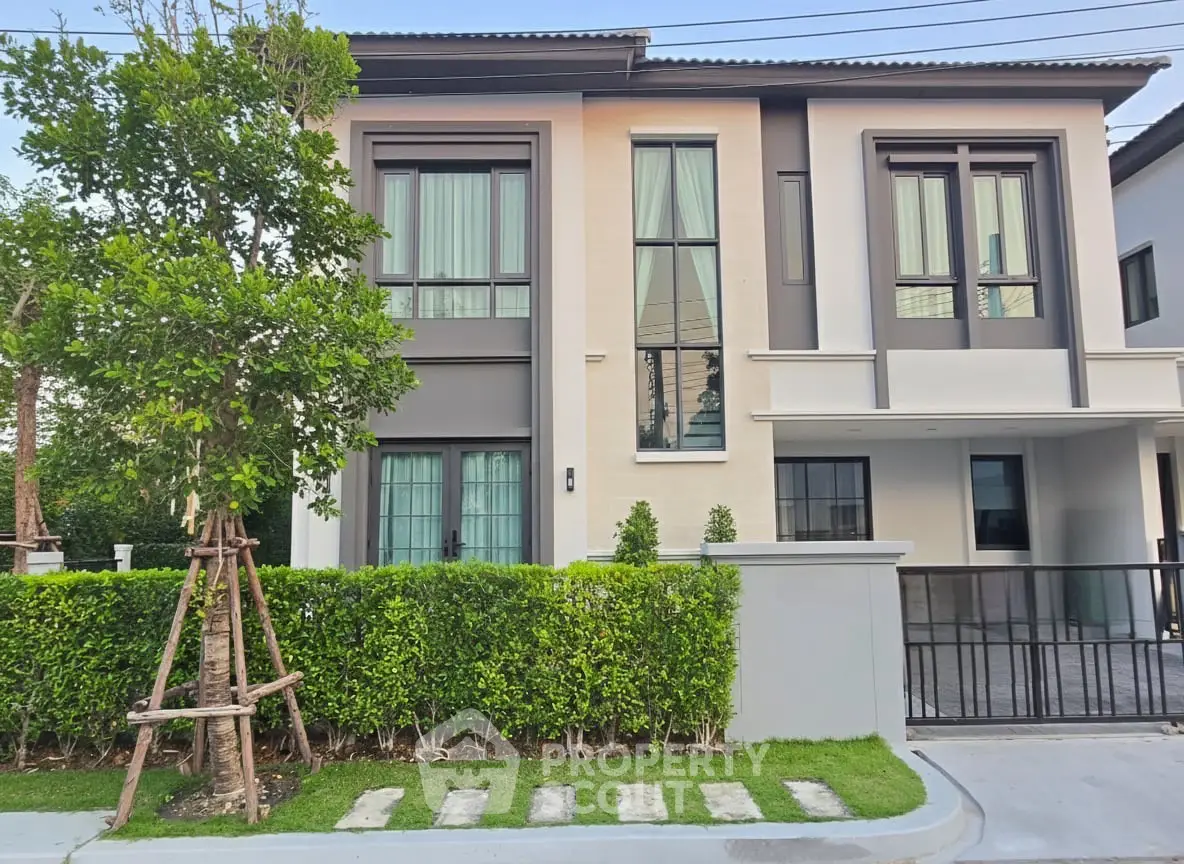 Modern two-story house with large windows and manicured garden