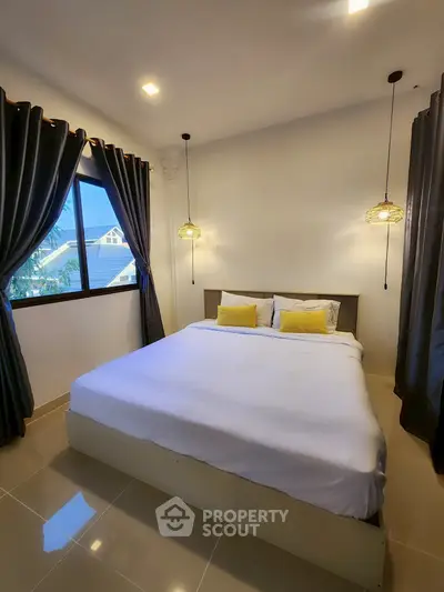 Cozy bedroom with modern lighting and large window offering natural light.