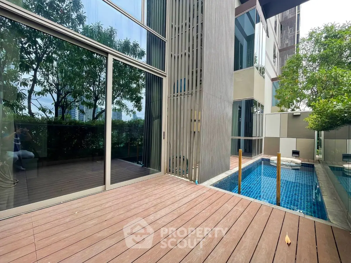 Luxurious modern apartment with private pool and spacious deck, surrounded by lush greenery.