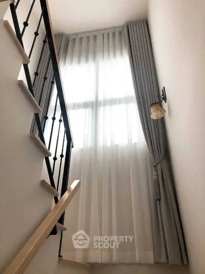 Elegant staircase with tall windows and luxurious curtains in modern home
