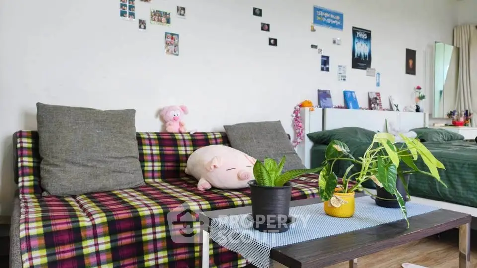 Cozy living room with plaid sofa, decorative plants, and wall art in modern apartment.