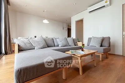 Spacious modern living room with stylish gray sectional sofa and wooden flooring.