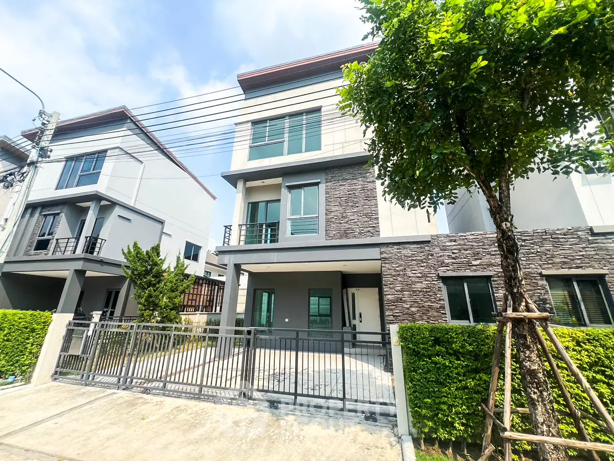 Modern three-story townhouse with gated driveway and lush greenery