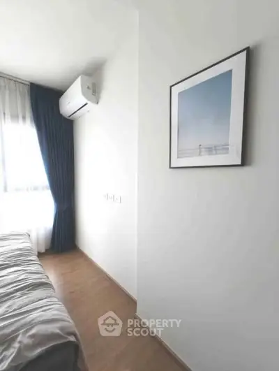 Modern bedroom with air conditioning and framed artwork, featuring natural light and wooden flooring.