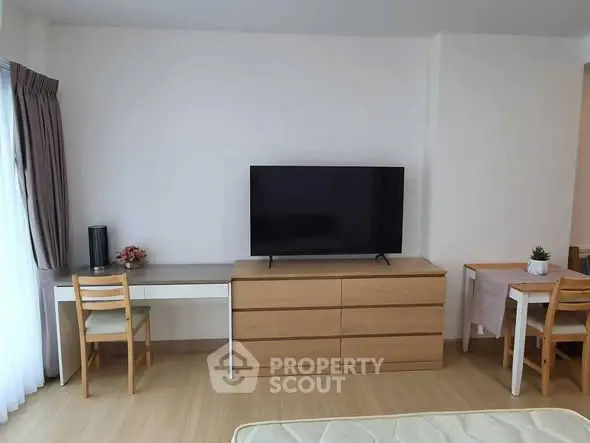 Modern living room with TV, wooden furniture, and natural light.