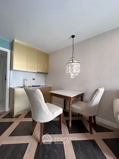 Chic dining area with elegant chandelier and modern kitchen corner in stylish apartment.