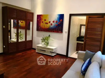 Elegant living room with wooden flooring and vibrant artwork, featuring a cozy seating area and stylish decor.